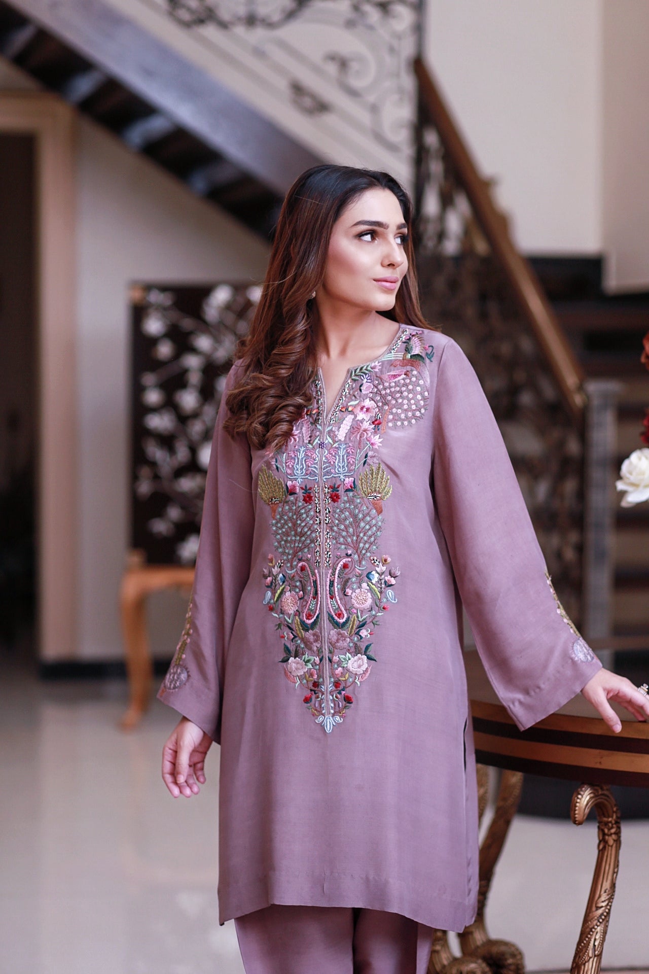 "Model wearing intricate mauve kurta with colorful embroidery, part of Eid Edit collection, in elegant indoor setting."